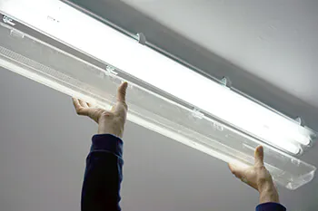 Hand installiert eine Philips LED-Röhre in eine Wannenleuchte